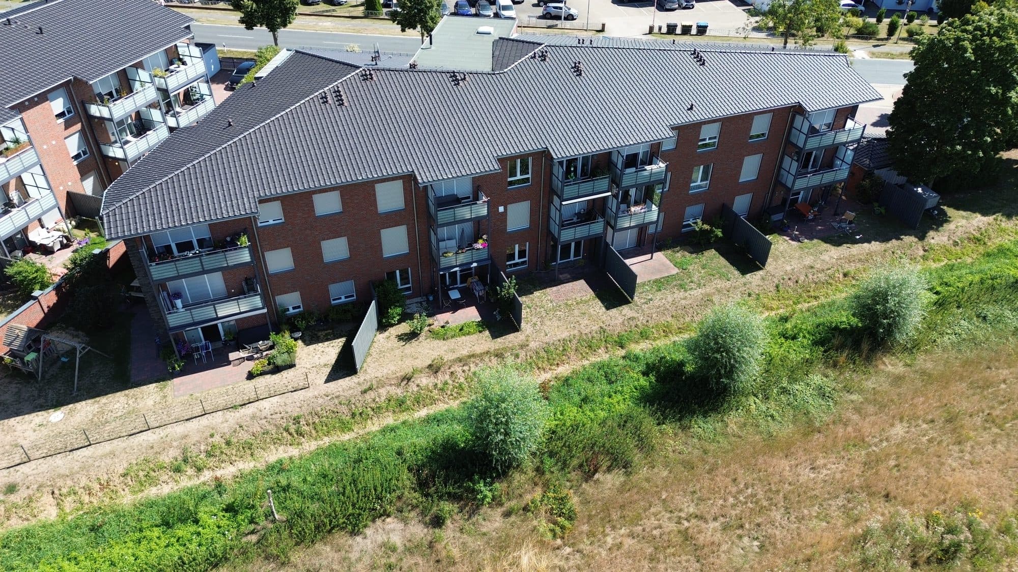 Außenvisualisierung Walsroder Straße 7, 30900 Wedemark – Gartenseite mit Balkonen, dahinter offene Feldflur